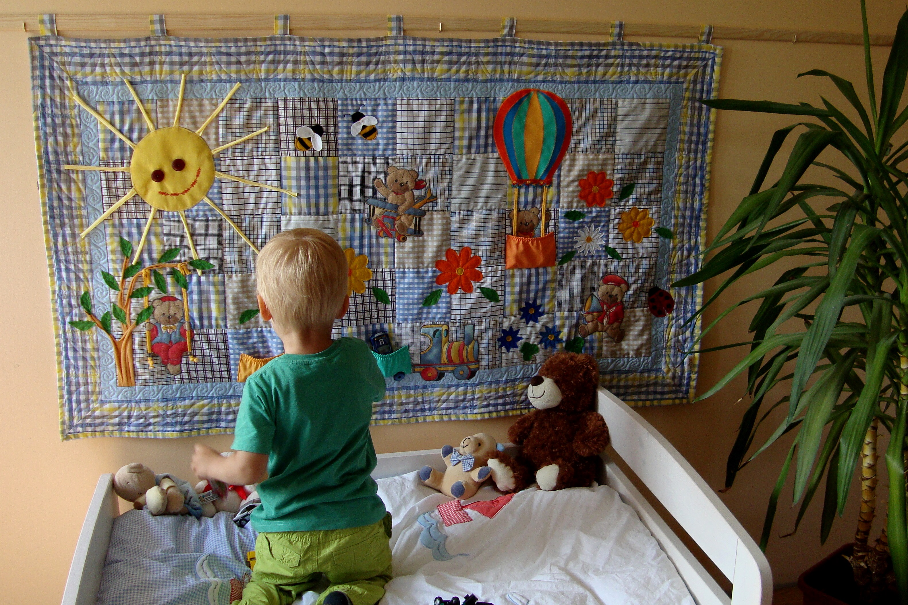 A child admiring a handmade sensory play blanket — sun, bears and a balloon, blue
